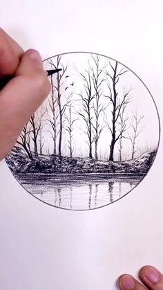 someone is drawing a landscape with black and white pencils on paper that has trees in the background