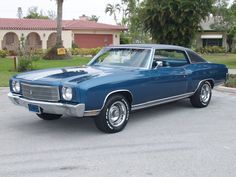 an old blue car is parked on the street