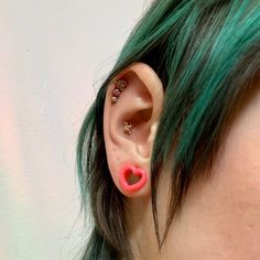 a woman with green hair and piercings on her ear