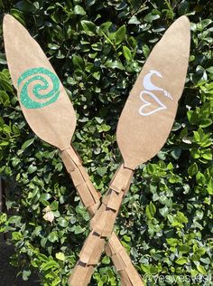 two wooden paddles with numbers on them are sitting in front of some green bushes