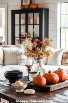 a coffee table with pumpkins and flowers in a vase sitting on top of it