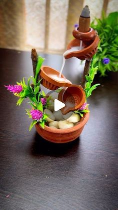 a clay pot filled with rocks and water pouring out of it on top of a wooden table