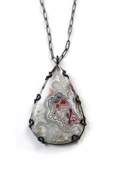 This stunning, one-of-a-kind necklace features a grey lace agate with pops of crimson and purple set in a custom-made steel setting suspended from a 30" oxidized silver chain. Perfect for tossing on over a t-shirt or sweater to instantly make any outfit pop! This stone is approximately 2 1/2” tall by 1 5/8" wide. Chain length: 30" long. Your necklace comes packaged in a gift box tied with a bow, a perfect way to treat yourself or a loved one. Caring for steel: Steel is a lightweight and durable Purple Set, Grey Lace, Oxidized Silver, Lace Agate, Chain Lengths, Silver Chain, Agate, Pendant Necklace, Chain