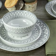 a table topped with plates and bowls filled with food next to green napkins on top of a wooden table