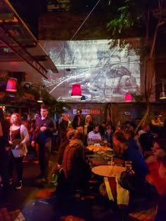 a group of people sitting at tables in a room with large screens on the wall