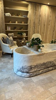 a bath tub sitting on top of a tiled floor next to a chair and table