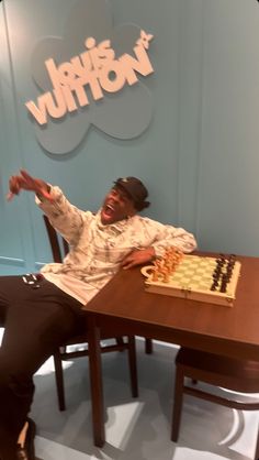 a man sitting at a table in front of a chess board with his arms outstretched