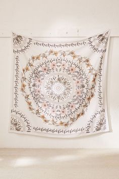 a tapestry hanging on the wall in a room with white walls and flowers around it