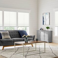 a living room filled with furniture and windows covered in shades of blue, grey and white