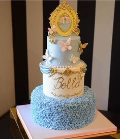 a three tiered cake with blue and white frosting on the top is decorated with butterflies