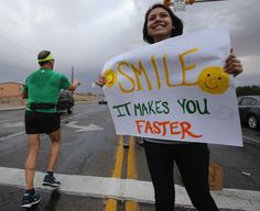 a woman holding a sign that says smile it makes you faster