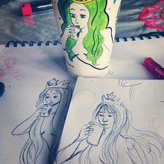 two drawings of princesses on paper next to a coffee cup