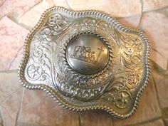 "This stunning silver tone belt buckle features an antique silver concho with a praying cowboy and horse drilled through an etched silver belt buckle lightly embellished with rhinestones. This is a great buckle for Men, Women and Children. The buckle is bright silver in color with a rope border. The buckle measures 3 1/2 x 2 3/4 and has a hook and D ring loop that attaches to any 1.5\" width belt strap. As with any internet purchase, please use these measurements against a buckle that you alread Adjustable Engraved Belt Buckles For Western-themed Events, Engraved Adjustable Western Belt Buckles, Vintage Silver Belt Buckles For Western-themed Events, Vintage Silver Concho Belt Buckles, Vintage Engraved Belt Buckles For Rodeo, Engraved Adjustable Belt Buckles For Rodeo, Adjustable Engraved Belt Buckles For Rodeo, Adjustable Antique Silver Belt Buckles, Silver Western Belt Buckles