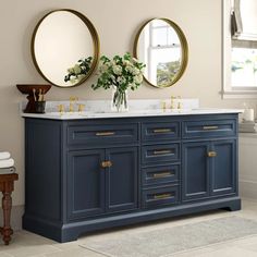 a bathroom with two round mirrors above the sink and blue cabinetry on the wall