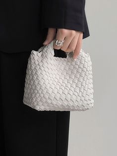 a person in a suit holding a white purse