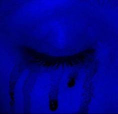 a woman's eye with blue light shining on it and water droplets all around her