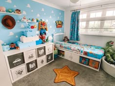 a child's bedroom decorated in blue and white with toy storage bins on the floor