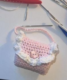 a crocheted purse sitting on top of a table next to some knitting needles