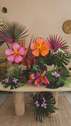 there is a table with flowers on it and plants in vases next to each other