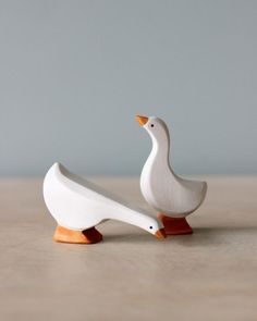 two white ceramic ducks sitting on top of a table