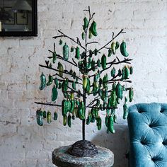 a tree made out of green glass bottles sitting on top of a table next to a blue chair