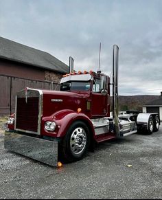 a red semi truck parked in front of a barn