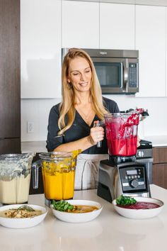 a woman standing in front of a counter filled with different types of food and blenders