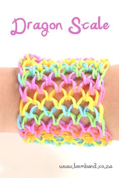 the bracelet is made with rainbow colored yarn and has a dragon scale design on it