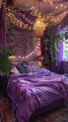 a bed with purple sheets and lights hanging from the ceiling above it in a bedroom