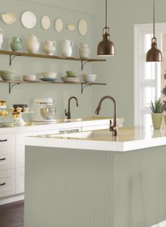 a kitchen filled with lots of counter top space and hanging lights over the sink area