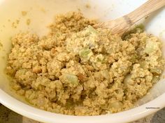 a white bowl filled with food next to a wooden spoon