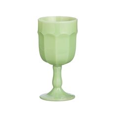 a green glass sitting on top of a white table