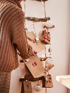 a woman standing next to a christmas tree with presents hanging from it's sides