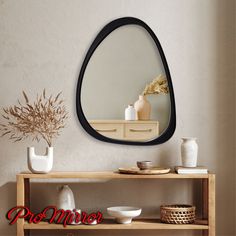 a mirror sitting on top of a wooden shelf next to a vase and bowl filled with flowers