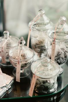 there are many glass jars on the table with tags attached to them and tied in twine