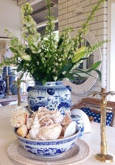 a blue and white vase sitting on top of a table next to a plate with sea shells