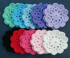 six crocheted coasters are arranged on the floor, each with different colors