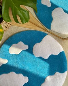 two blue and white rugs with clouds on them next to a potted plant