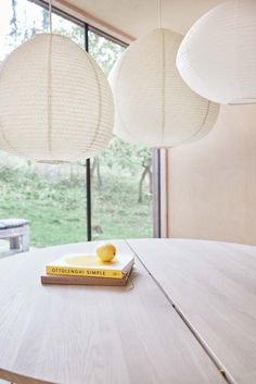 two lamps hanging from the ceiling above a table with a book on top of it