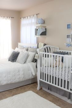 a baby's room with a crib, bed and window