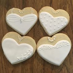 four decorated heart shaped cookies sitting on top of a wooden table