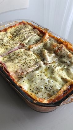 a casserole dish with meat, cheese and sauce in it on a table