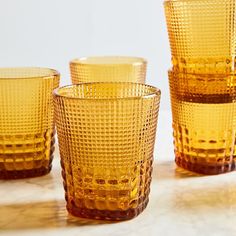 four yellow glass cups sitting on top of a table