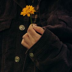 a person holding a yellow flower in their left hand with buttons on the other side