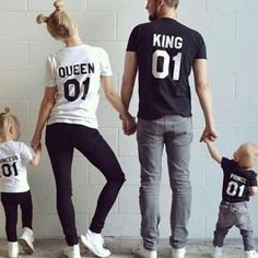 a man and two women holding hands while standing next to a little boy in front of a white brick wall