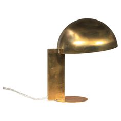 a brass colored table lamp with a white cord attached to the base and a light bulb on top