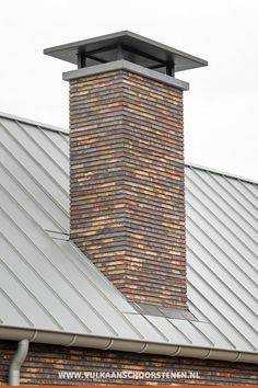 a brick chimney on top of a building with a metal roof and red brick walls