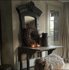 a table with candles on it in front of a mirror and some vases next to a bench