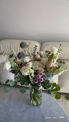 a vase filled with flowers sitting on top of a table next to a white couch