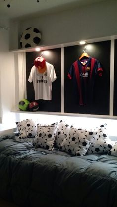 a bed with pillows and soccer jerseys on the wall